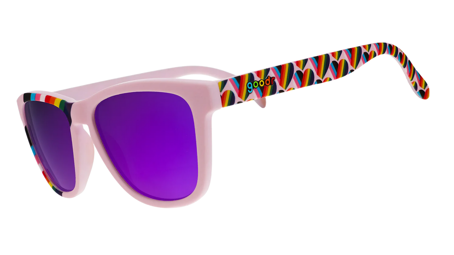 goodr We're Here to Slay. Exklusiva Pride-solglasögon från goodr med stilrena lavenderlila bågar med hjärtan i regnbågsfärger längst med bågarna och en regnbågsflagga över ena bågen