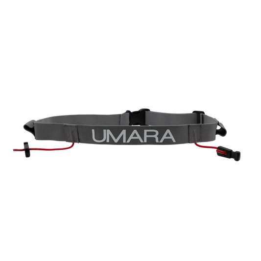 Umara Nummerlappsbälte. Håller nummerlappen på plats och gör flytt av nummerlapp enkelt. Grått bälte med vit text "UMARA"